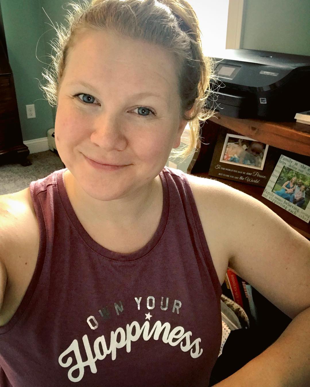 Coach in home office wearing own your happiness shirt